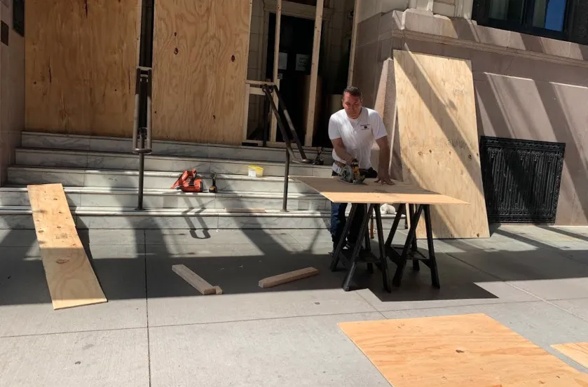 man cutting plywood for a property board up
